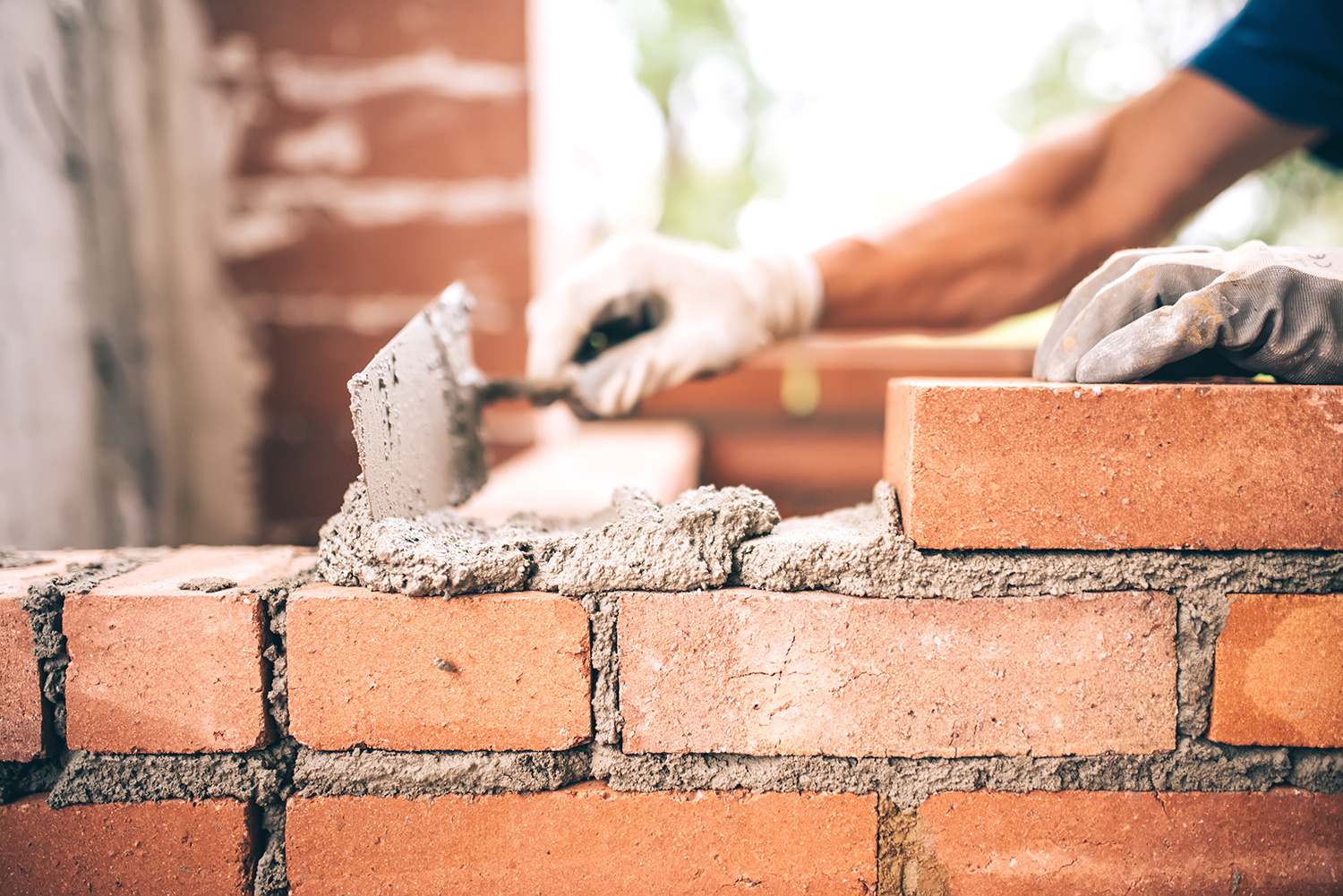 Brick and Mortar Mansonry Supplies Construction Worker Laying Brick with a Hand Trowel